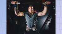 fit, muscular man doing pull-ups in dark gym