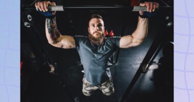 fit, muscular man doing pull-ups in dark gym