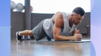 muscular, determined man holding a forearm plank on yoga mat in workout space