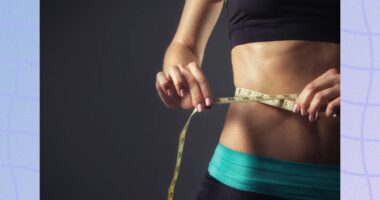 close-up of woman in sports bra and yoga pants measuring her waistline