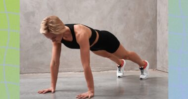 fit blonde woman doing high plank exercise in front of gray wall