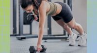 fit brunette woman doing dumbbell renegade row exercise