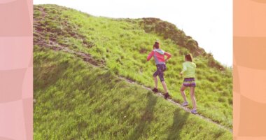 two fit female friends walking uphill, hiking for exercise on sunny day