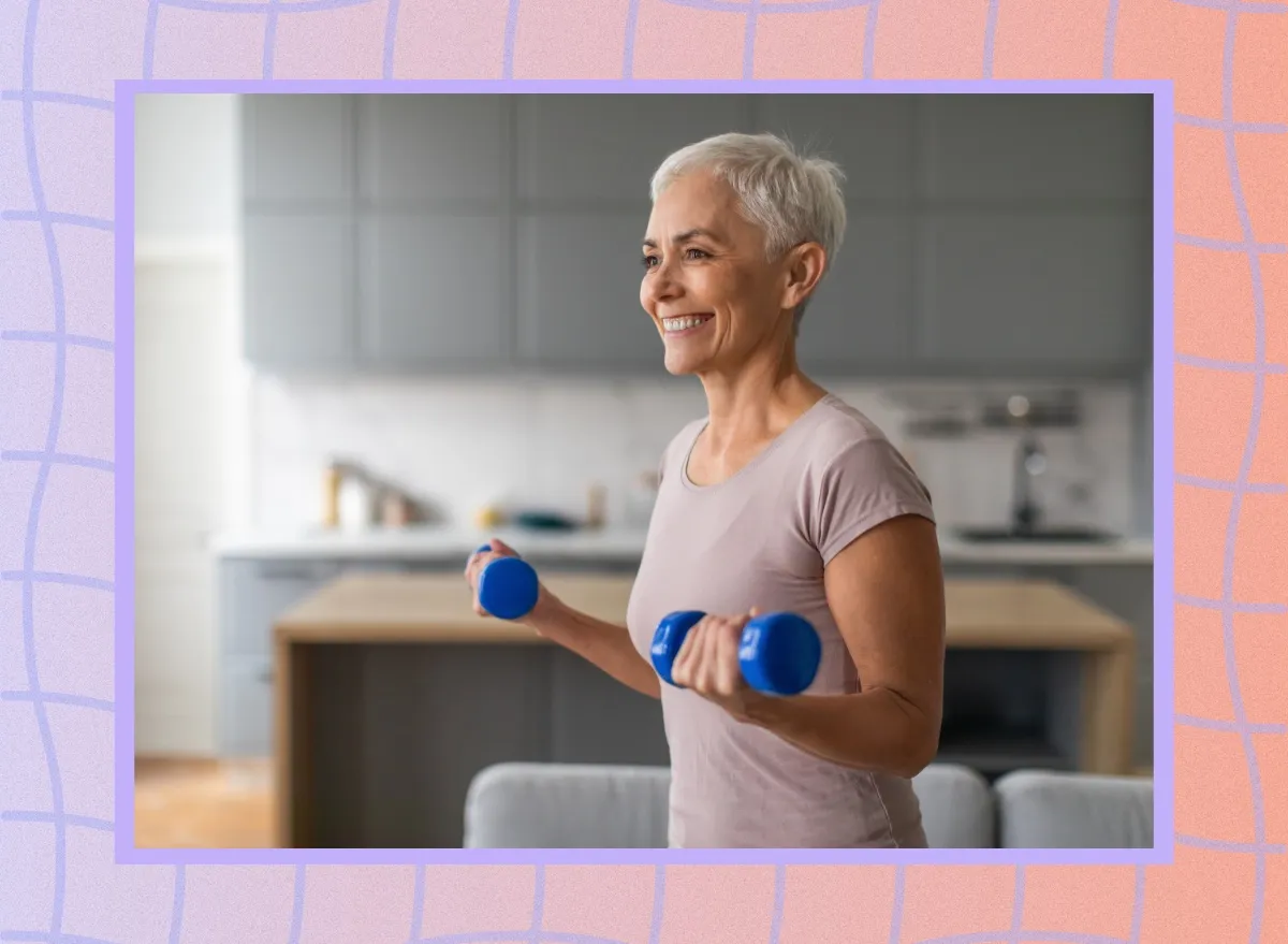 mature, happy woman lifting dumbbells in her living room