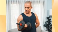 fit, mature man doing bicep curl in living space in front of couch and curtains