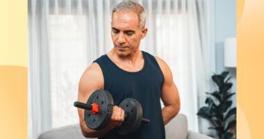 fit, mature man doing bicep curl in living space in front of couch and curtains