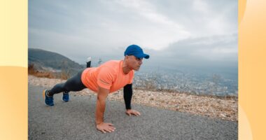 fit, mature man doing high plank or pushups on side of the road with mountains in the background