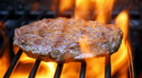 Juicy beef burger sizzling over hot flames on the barbecue