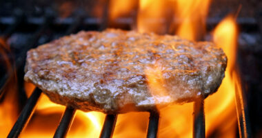 Juicy beef burger sizzling over hot flames on the barbecue