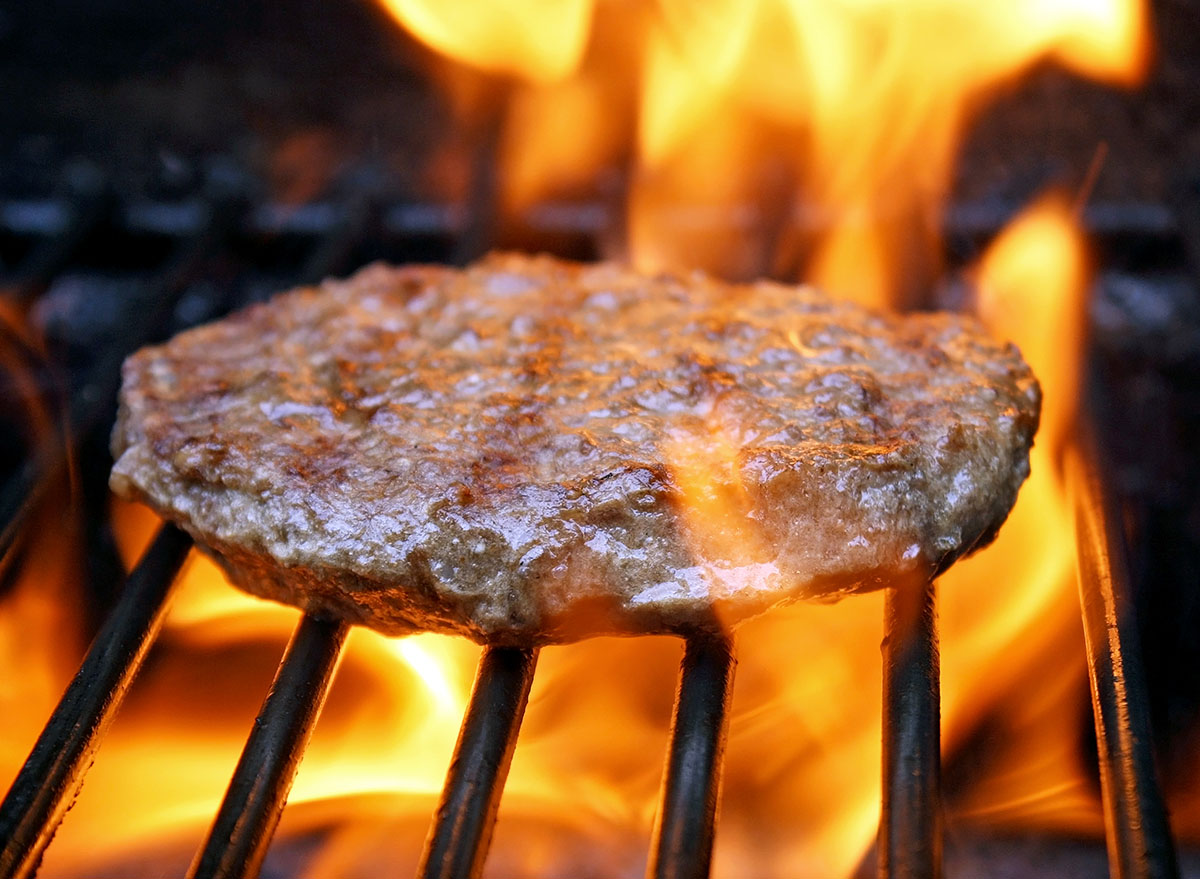 Juicy beef burger sizzling over hot flames on the barbecue