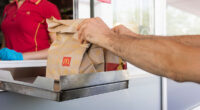 McDonalds service the Drive-Thru due to coronavirus. Employee in gloves, order in window. Contactless transfer.