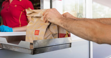 McDonalds service the Drive-Thru due to coronavirus. Employee in gloves, order in window. Contactless transfer.