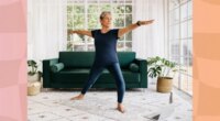 mature woman doing a balance yoga exercise in bright living room