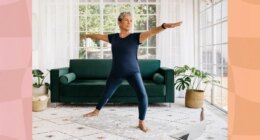 mature woman doing a balance yoga exercise in bright living room