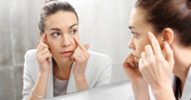 Woman checking wrinkles in front of the mirror.