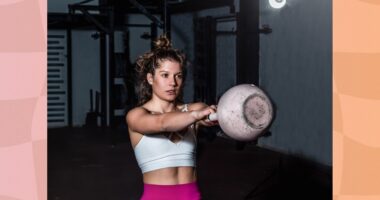 fit, focused woman doing kettlebell swing in dark gym