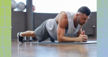 fit, muscular man holding a forearm plank on workout mat at the gym