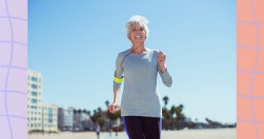 fit, mature woman power walking on the beach on sunny day