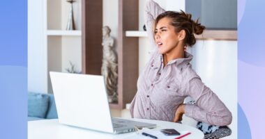 woman stretching and experiencing back pain while seated at her desk