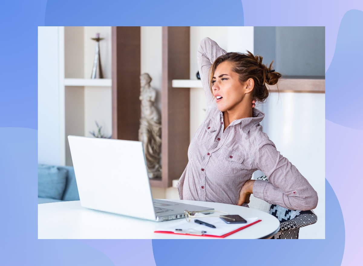 woman stretching and experiencing back pain while seated at her desk