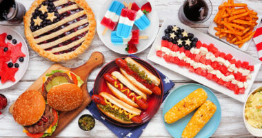 Fourth of July, patriotic, American themed food. Overhead view table scene on a white wood background.