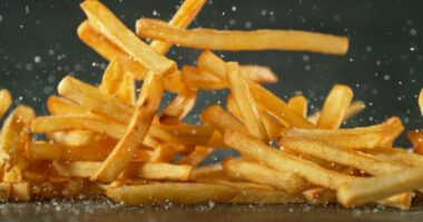 Flying French Fries Falling on Table. Fast Food Concept with Flying Food.