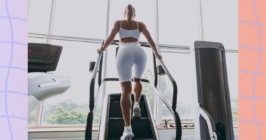 backside view of woman doing a stair climber workout at the gym in front of windows