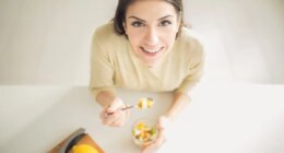 Healthy looking cheerful woman eating homemade organic fruit mix fruit salad.Fruit diet,dieting,nutrition,vegetarian concept.Food for beautiful skin,strong immune system,diet fitness meal.Heathy snack