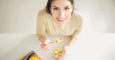 Healthy looking cheerful woman eating homemade organic fruit mix fruit salad.Fruit diet,dieting,nutrition,vegetarian concept.Food for beautiful skin,strong immune system,diet fitness meal.Heathy snack