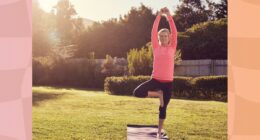 senior woman in pink long-sleeve top and black leggings doing balancing exercise or tree pose on yoga mat in sunny backyard