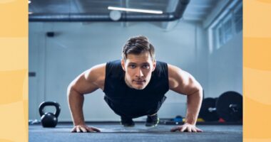 man doing pushups in a dark gym