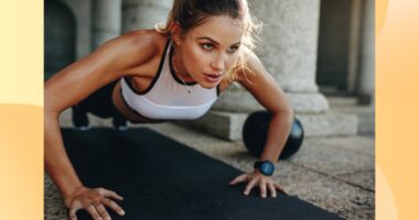 focused woman doing pushups on black yoga mat