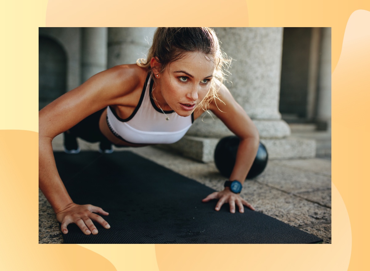 focused woman doing pushups on black yoga mat