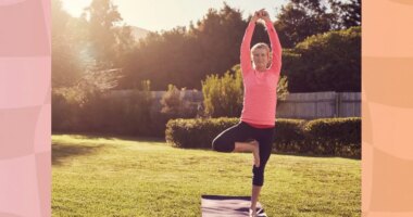 senior woman in pink long-sleeve top and black leggings doing balancing exercise or tree pose on yoga mat in sunny backyard