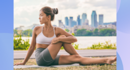 woman in sports bra and biker shorts stretching outdoors on yoga mat in front of city backdrop