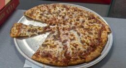 Honolulu - August 15, 2024: A freshly baked pizza sits on a metal tray, with a few slices taken, ready to be enjoyed at a lively Chuck E. Cheese venue in Hawaii.