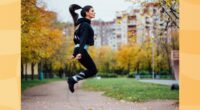 fit brunette woman doing jump rope workout outdoors on autumn day