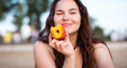 Girl eats juicy peach on the beach. Ripe peach.