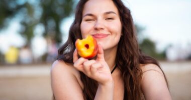 Girl eats juicy peach on the beach. Ripe peach.