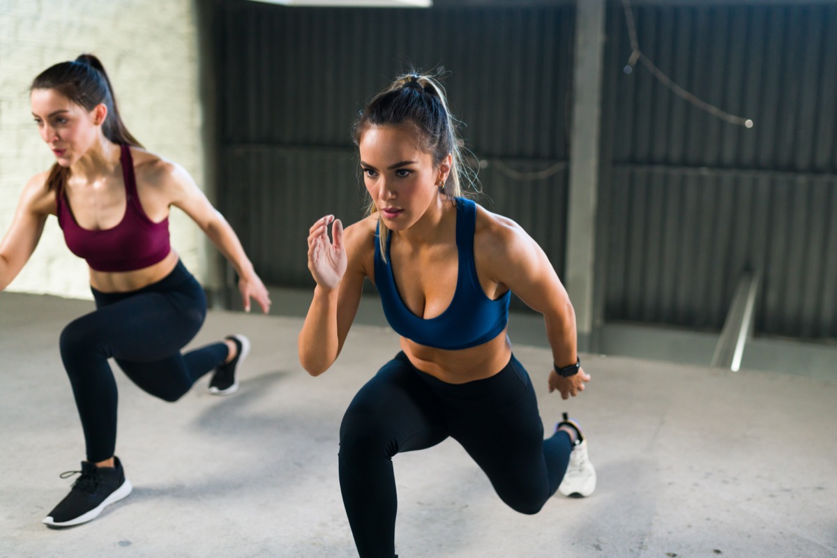 Athletic young woman with a healthy lifestyle doing leg lunges during a HIIT class. Women working out together at the fitness center