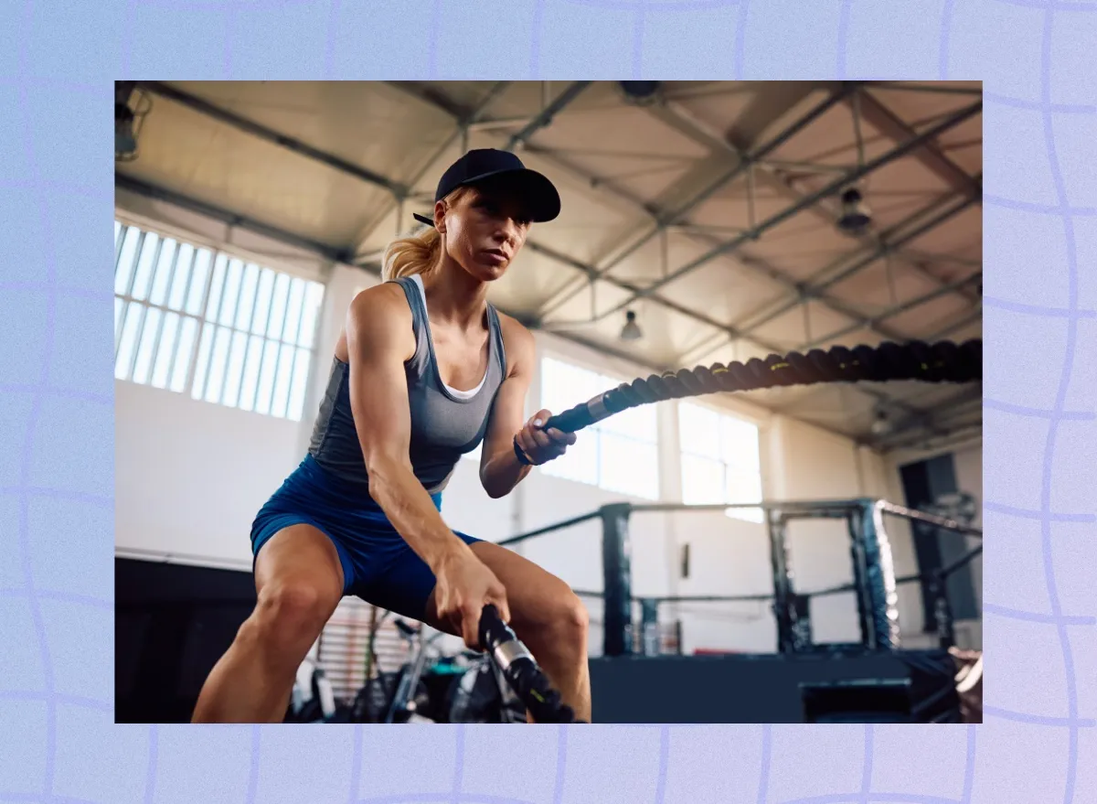 fit, determined blonde woman using battle ropes in boxing gym