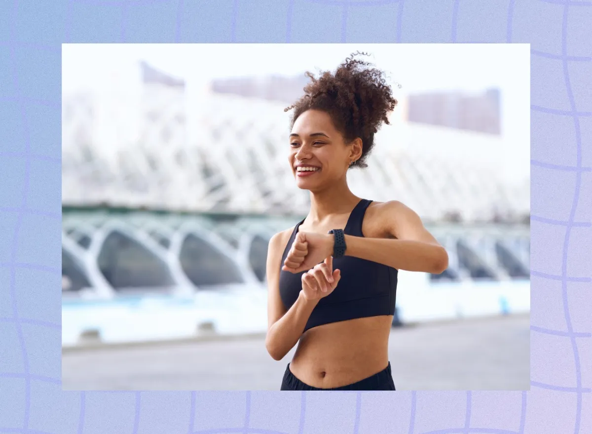 happy woman checking her fitness tracker while outdoors on a walk