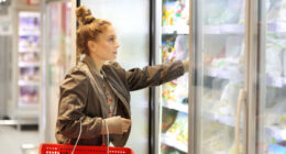 woman choosing frozen food in freezer aisle