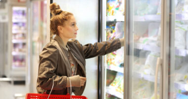 woman choosing frozen food in freezer aisle